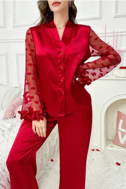 Woman wearing a red satin pajama set with sheer heart-patterned sleeves.