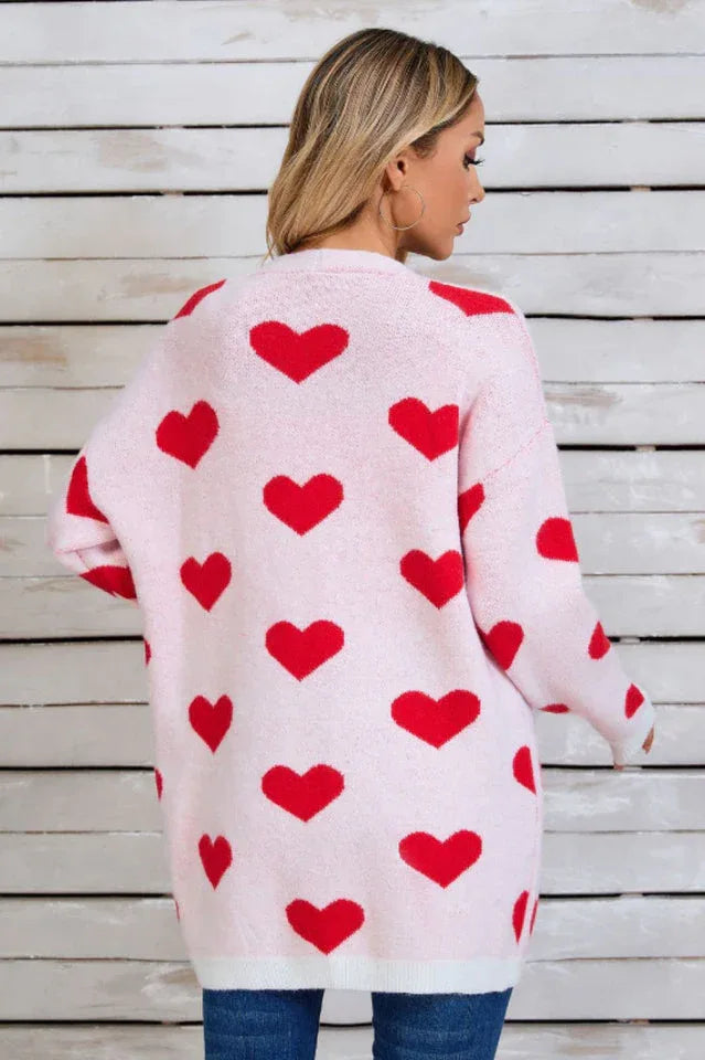 Back view of a woman wearing a pink longline cardigan with a red heart print.