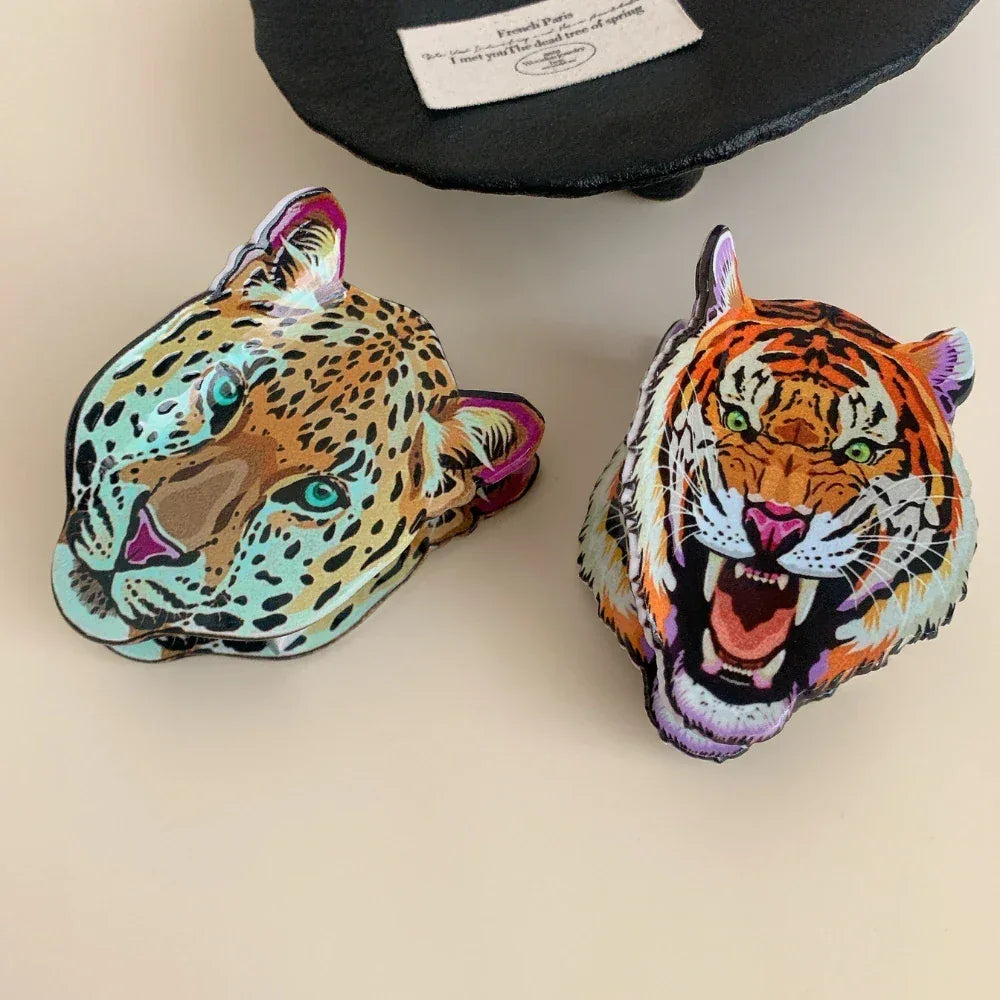 Two animal head accessories, a leopard and a tiger, placed side-by-side on a light-colored surface