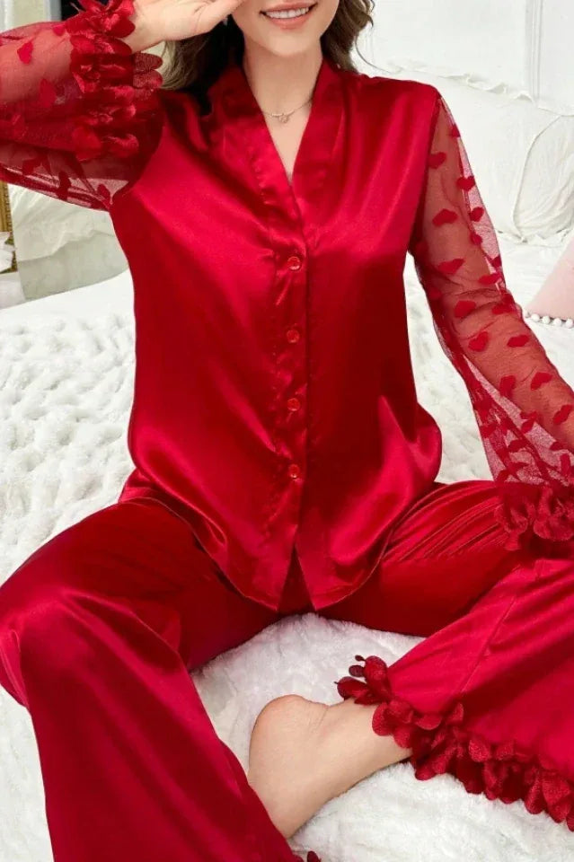 Woman sitting on a bed wearing a red satin pajama set.