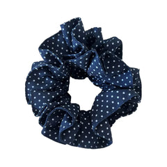 A single navy blue and white polka dot scrunchie