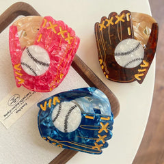 Three marbled acrylic baseball glove hair claw clips in pink, brown, and blue