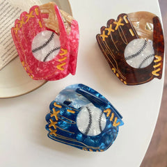 Arrangement of three marbled acrylic baseball glove hair claw clips on a white surface