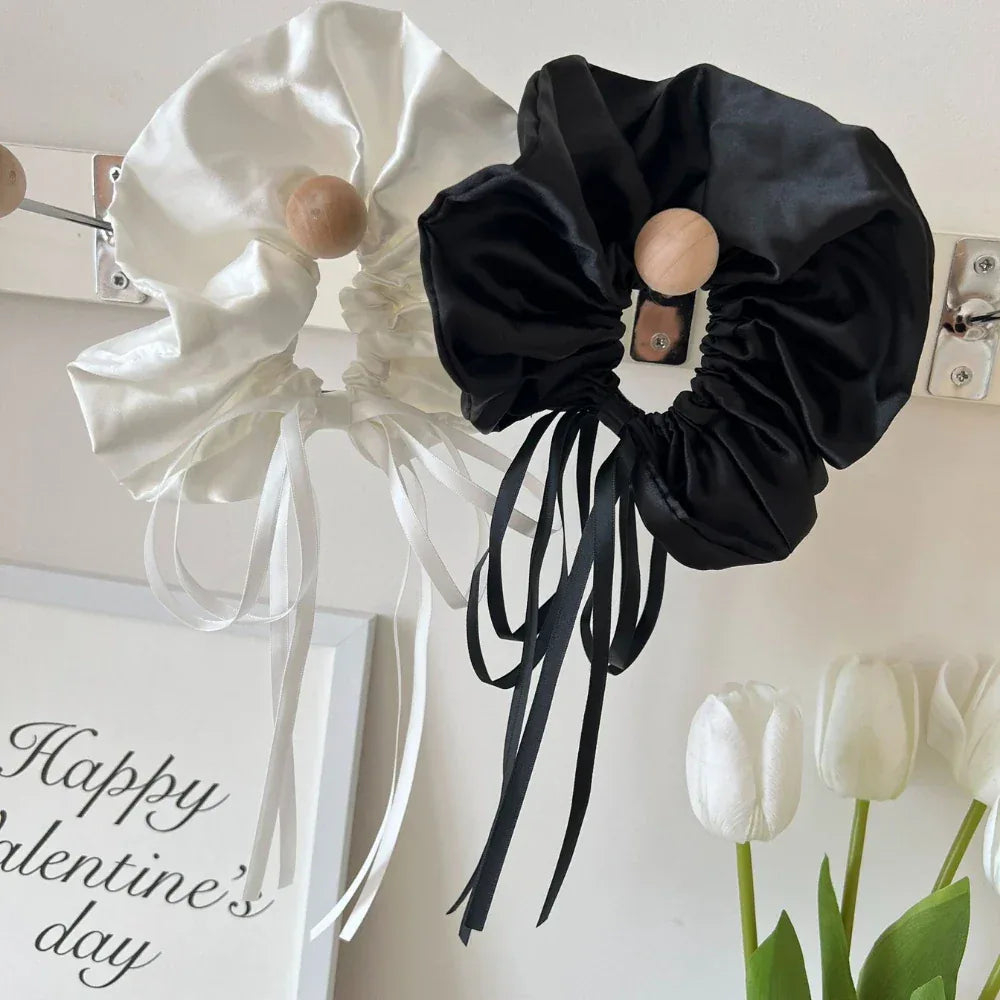 black and white satin scrunchies with long ribbon ties hanging on a wall
