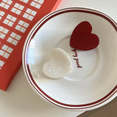 White and red heart-shaped hair clips on a saucer