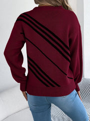 Back view of a woman wearing a burgundy knit sweater with black diagonal stripes, blue jeans.