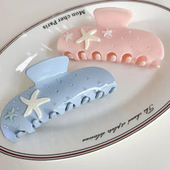 light blue and pink pastel claw clips with starfish and rhinestones, presented on a white oval dish