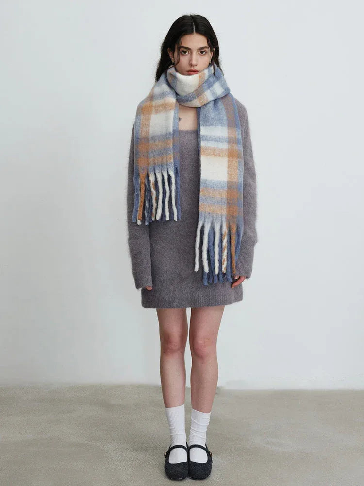 Full body shot of a woman in a grey knit dress and plaid scarf