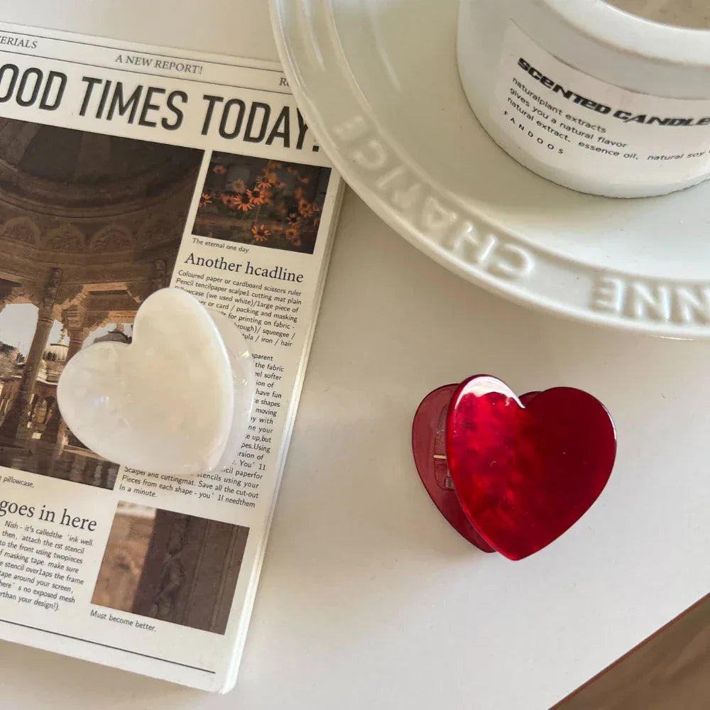 White and red heart-shaped hair clips next to a newspaper