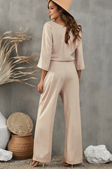 back view of a beige wide leg jumpsuit with a tie waist and keyhole detail