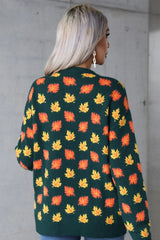 Back view of a woman wearing a dark green sweater adorned with an all-over maple leaf print in orange and yellow.