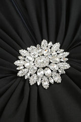 Close-up of a sparkling, multi-faceted jeweled brooch on a black ruched dress.