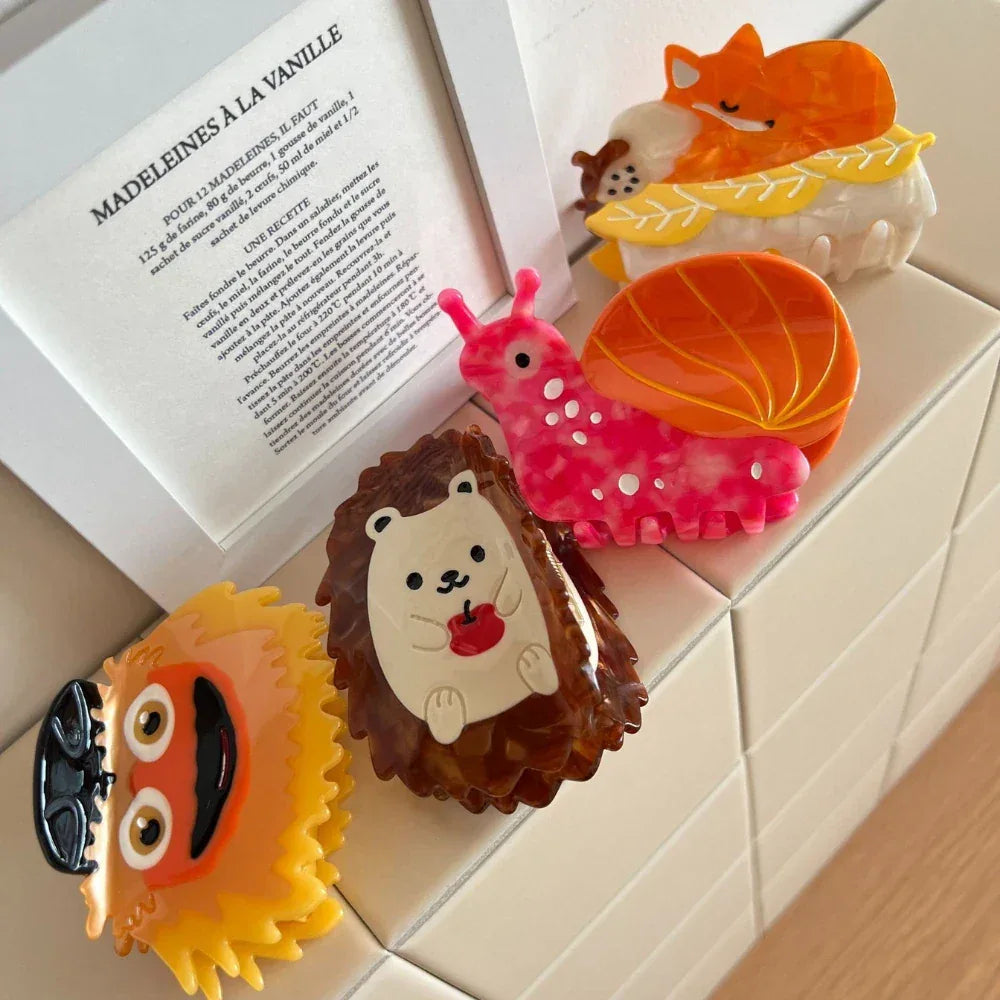 A collection of animal-themed hair clips including a fox, snail, hedgehog, and a fuzzy character.