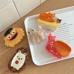 Various animal and character hair clips arranged on a white tray.