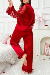 Back view of a woman in a red satin pajama set with ruffled details.