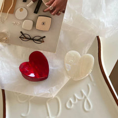 White and red heart-shaped hair clips on a tray