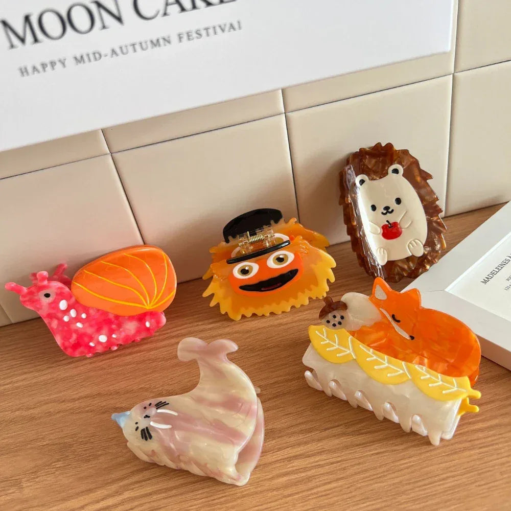 A variety of novelty hair clips including a hedgehog, snail, fox, seal, and a fuzzy character.