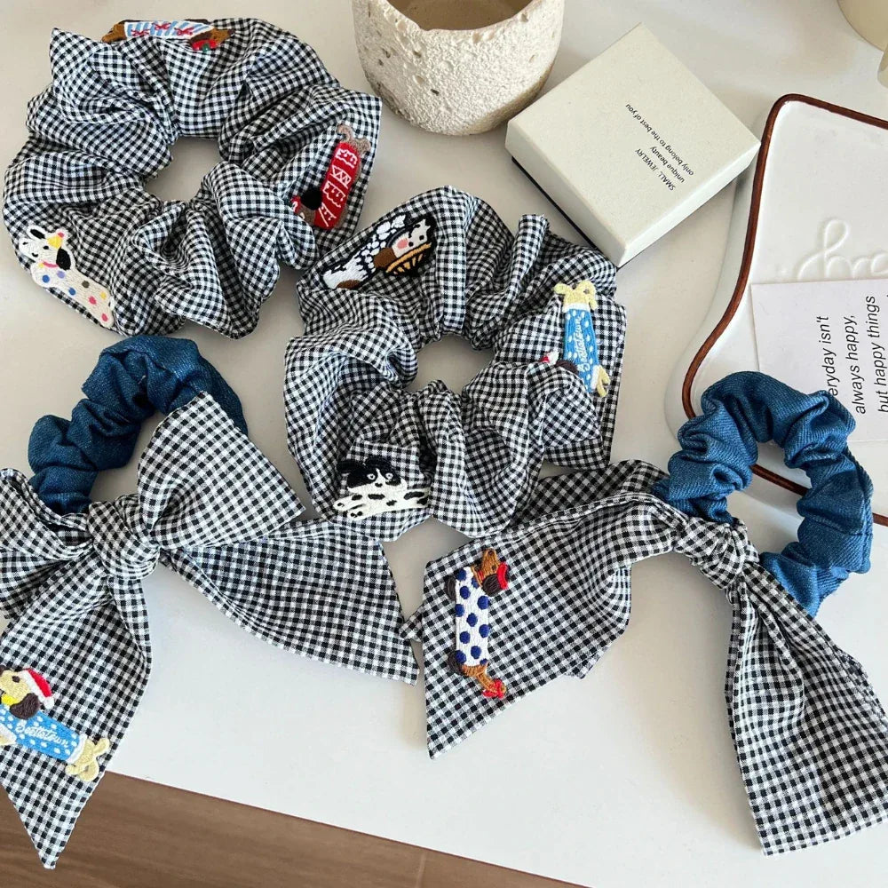 Collection of black and white gingham scrunchies with various embroidered dog appliques and denim accents