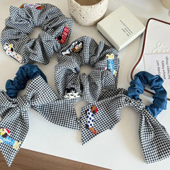 Collection of black and white gingham scrunchies with various embroidered dog appliques and denim accents