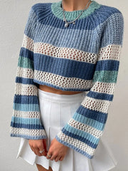 Front view of a woman in a blue and white striped crochet knit cropped sweater with bell sleeves and a white pleated mini skirt.