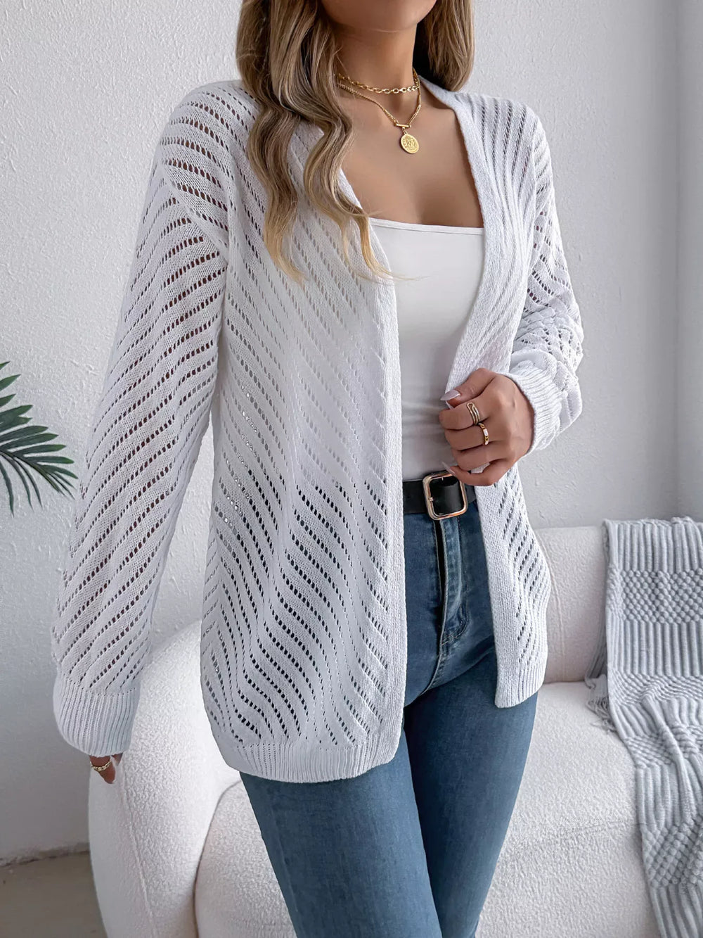 Close-up of a woman wearing a white open-knit cardigan, showing the texture and detail.