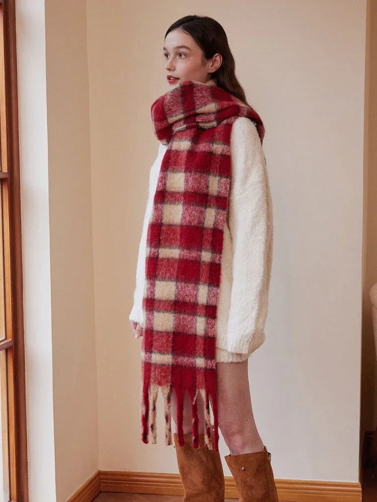 Side view of a woman wearing a red and cream plaid scarf and a white sweater, paired with brown boots.