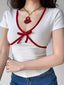 Woman wearing a white short-sleeved top with red trim and a red bow detail.