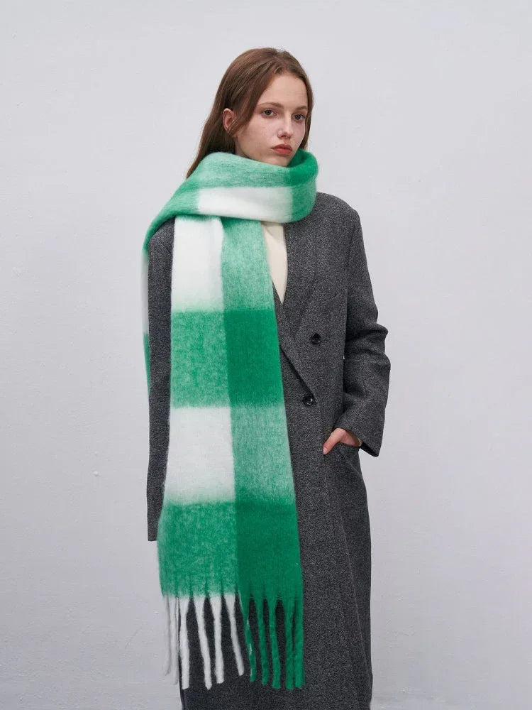 Woman wearing a grey coat and a green and white plaid scarf with fringe.