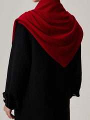 Woman wearing a red scarf draped over a black coat, back view