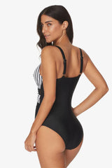 Back view of a woman in a black and white striped and black one-piece swimsuit with mesh detailing