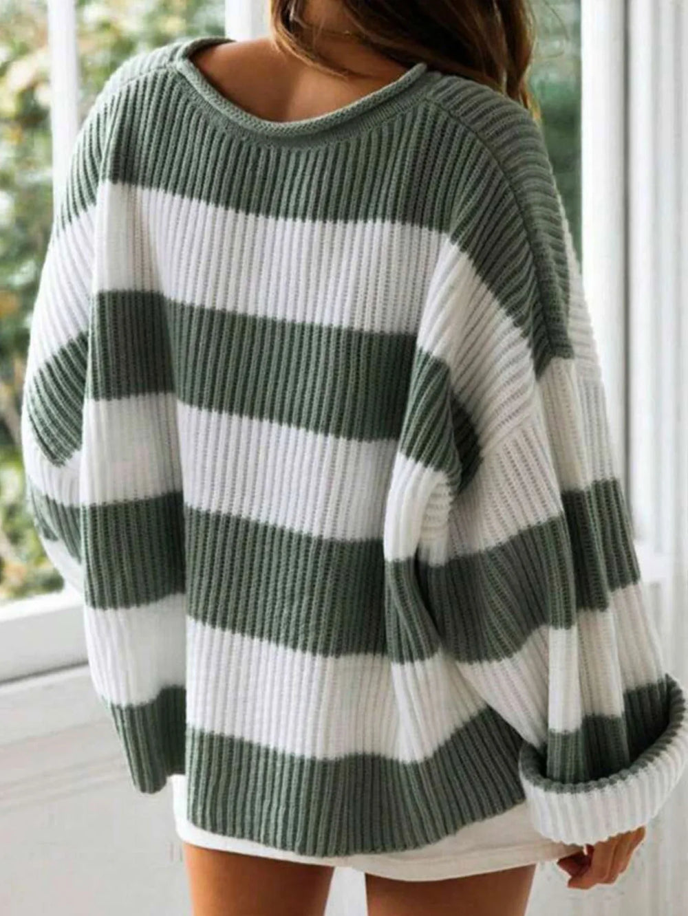 Back view of a woman wearing a green and white striped knit sweater with a crew neck.