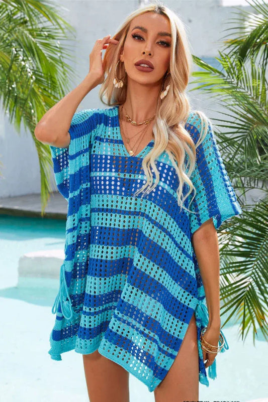 Woman wearing a blue and teal striped crocheted poncho with a V-neck and short sleeves by a pool.