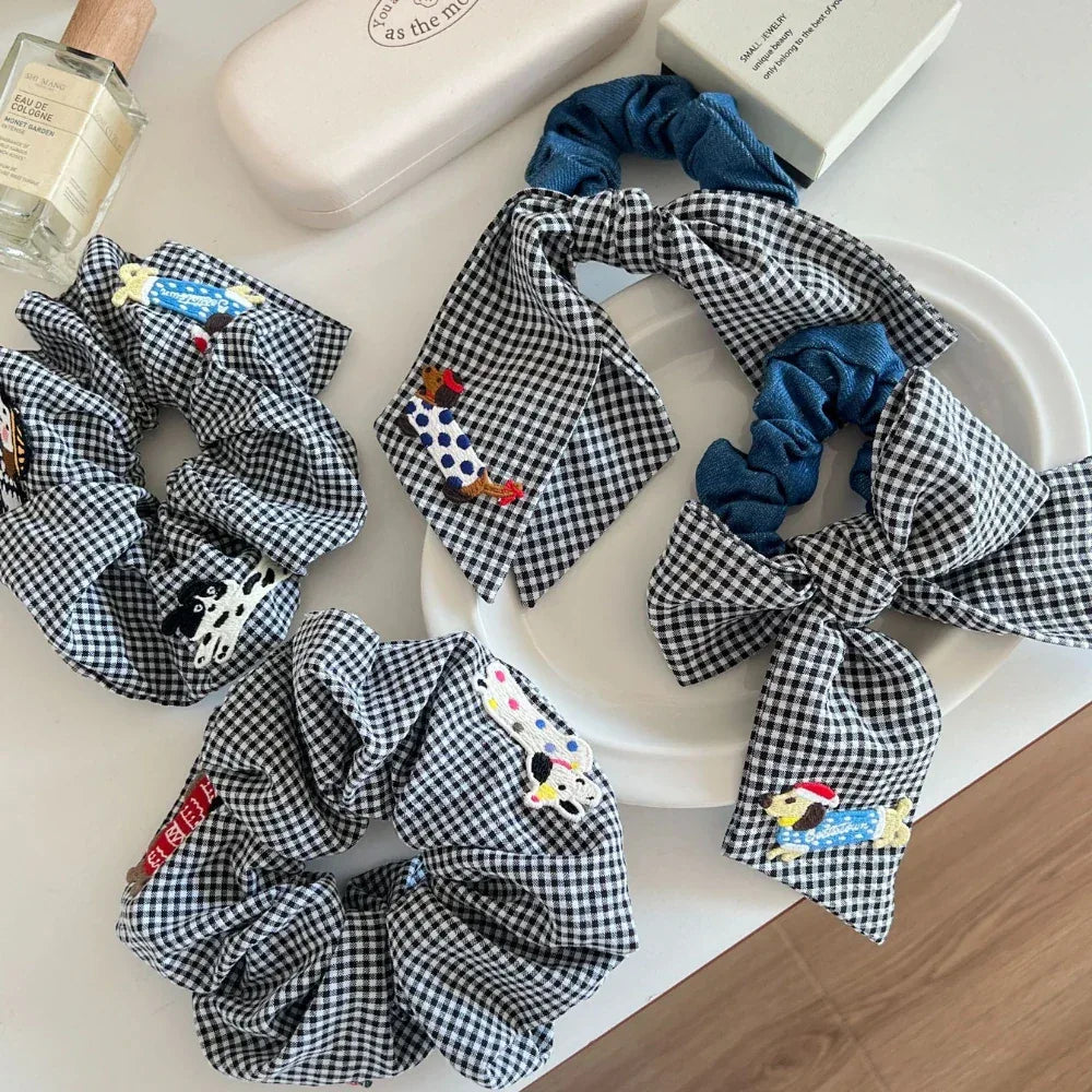 Close-up of black and white gingham scrunchies with denim bows, showcasing embroidered dog designs