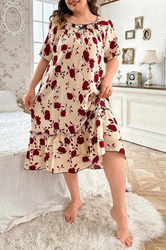Plus size woman in a cream and red floral print short sleeve ruffled hem nightgown standing in a bedroom.
