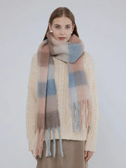 Woman wearing a cream cable knit sweater and a plaid scarf with pink, blue, and brown stripes.