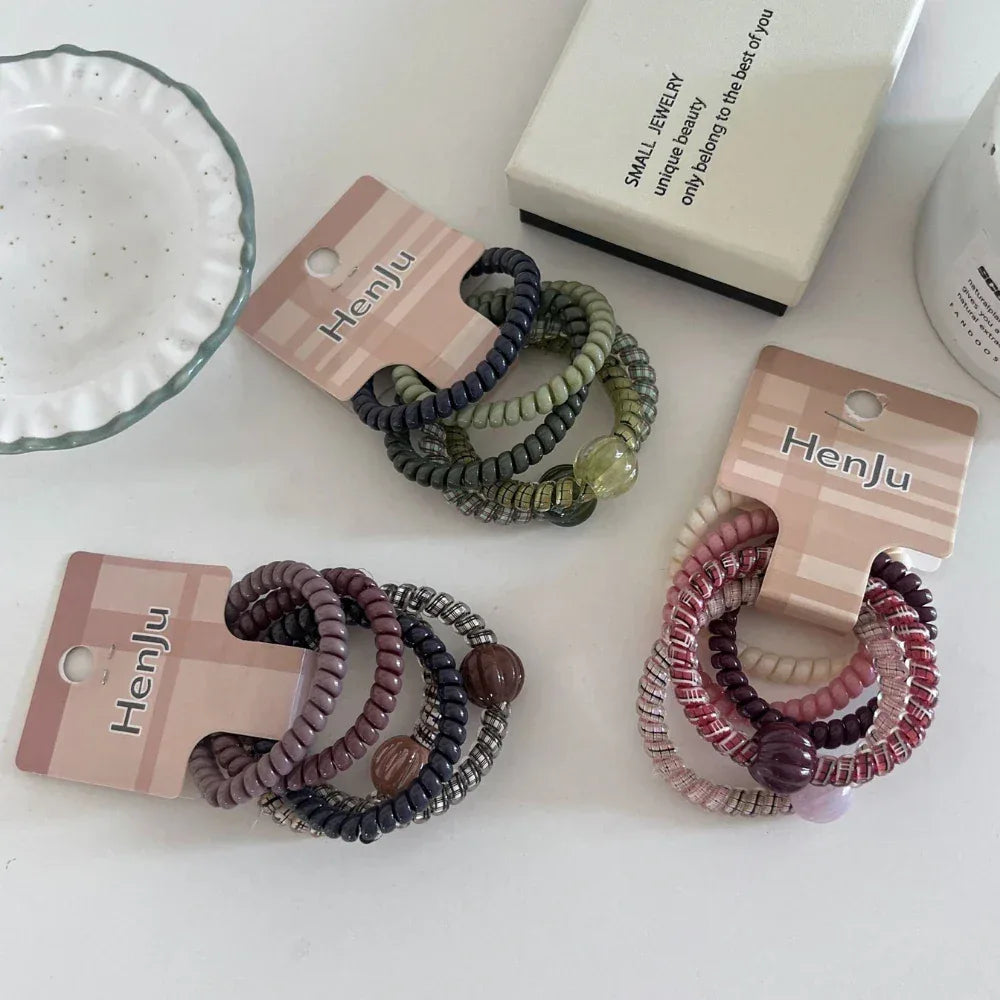 Three packs of spiral hair ties arranged on a white surface with other decorative items.