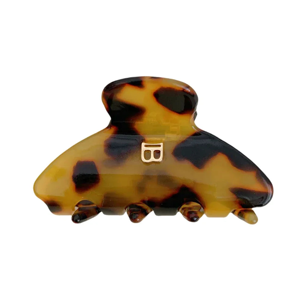 A tortoiseshell pattern claw hair clip with a gold-tone 'B' logo.
