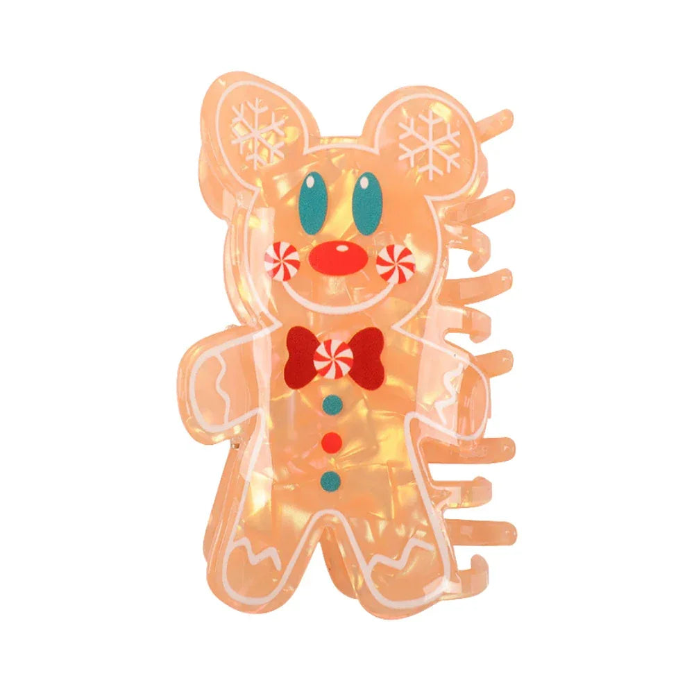 Close-up of an orange gingerbread man hair claw clip with white frosting details and red and blue candy buttons.