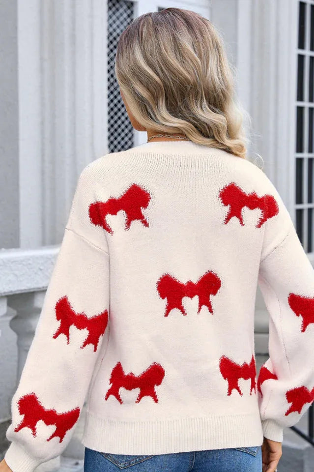 Back view of a woman wearing a cream knit sweater with a red bow pattern