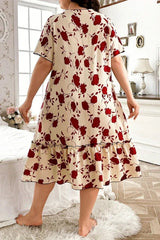 Plus size woman in a cream and red floral print short sleeve ruffled hem nightgown standing with her back to the camera in a bedroom.
