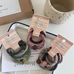 Multiple packs of spiral hair ties displayed on a tray with packaging.