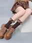 Close-up of brown ribbed socks with ruffled butterfly trim and brown lace-up platform shoes.