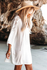 Woman in a white bohemian-style dress with lace sleeves and a straw hat walking on a beach