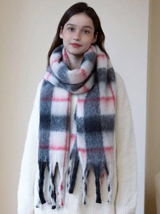 Woman wearing a cream-colored sweater and a plaid scarf with white, pink, and gray colors.