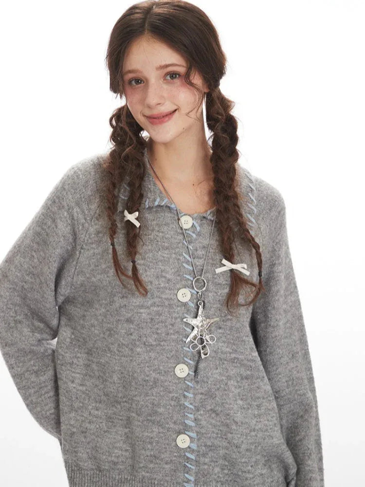 Close-up of a model wearing a grey knitted cardigan, highlighting the buttons, stitching, and necklace.