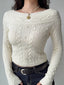 Close-up of a cream cable knit cropped sweater with an off-the-shoulder neckline and button details.