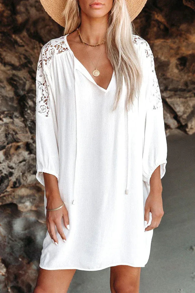 Close-up of a woman wearing a white bohemian-style dress with lace sleeves and a straw hat