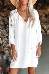 Close-up of a woman wearing a white bohemian-style dress with lace sleeves and a straw hat