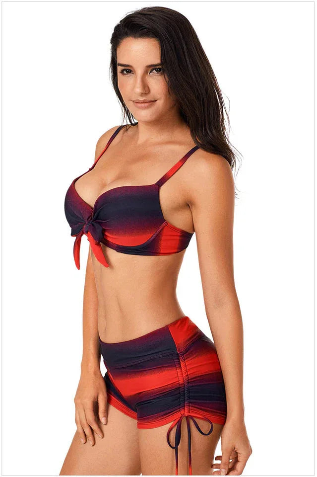 Woman wearing a red and black gradient stripe bikini with a bow detail, profile view