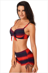 Woman wearing a red and black gradient stripe bikini with a bow detail, profile view